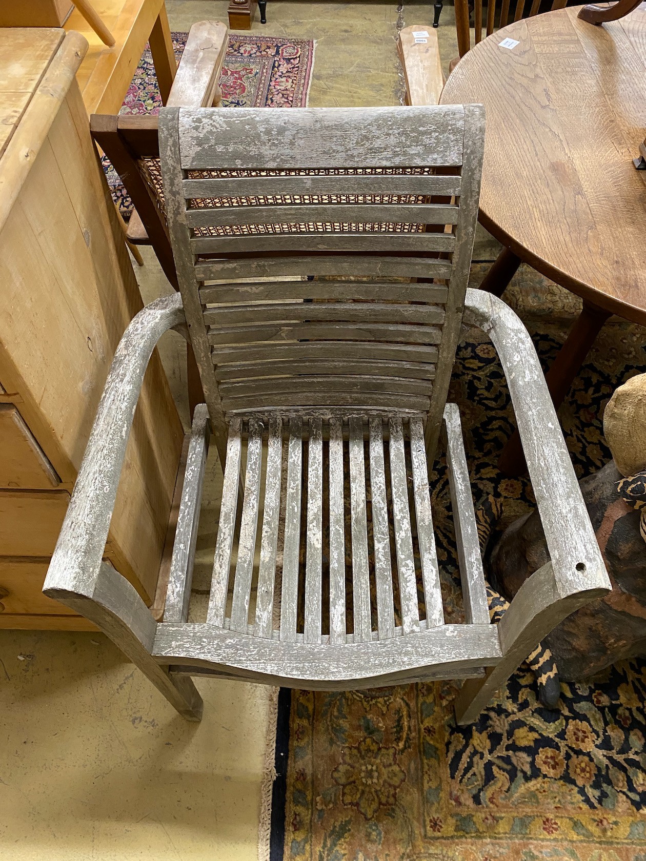 A pair of weathered teak slatted garden elbow chairs, width 65cm, depth 45cm, height 95cm
